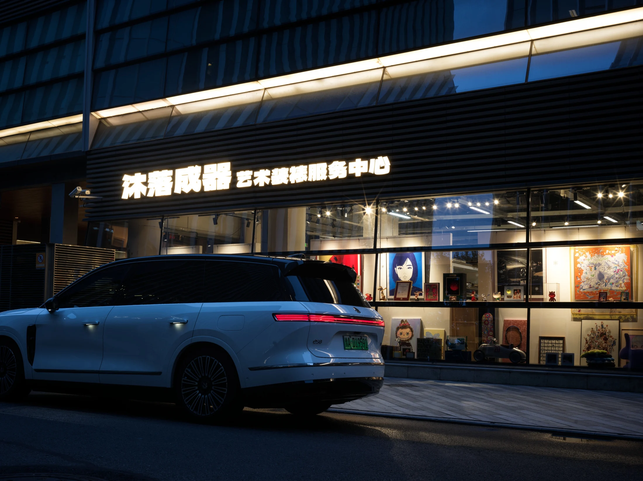 沐落成器艺术装裱工作室夜景外观，发光门头与落地橱窗中的作品陈列